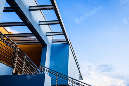 Preview: Staircase and terrace of a building with blue and orange walls, with copy space and blue sky
