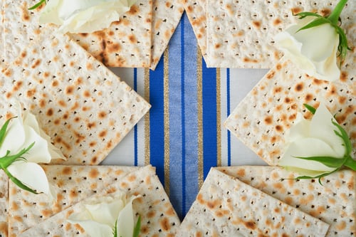 Preview: Passover celebration concept. Blue Star of David made from matzah, white and yellow roses, kippah an