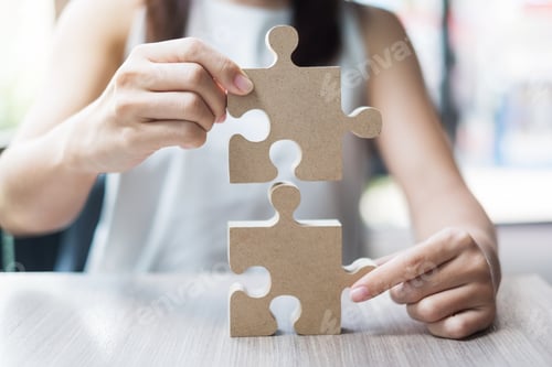 Preview: Woman hands connecting couple puzzle over table, businessman holding wood jigsaw inside office