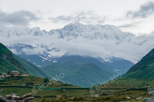 Preview: view of green grass meadow with houses and buildings and mountains on background, Ushguli, svaneti,
