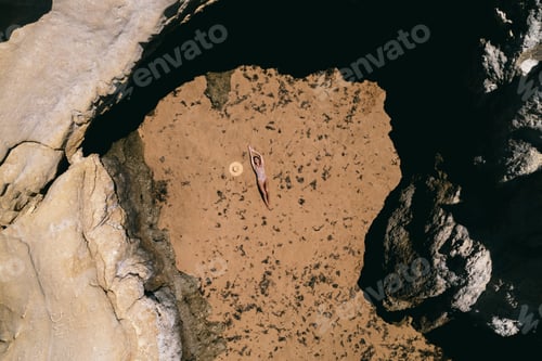 Preview: Tanned young lady relaxing on rocky coast in summer