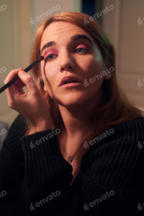 Preview: Young woman makes up her eyelashes in front of a mirror