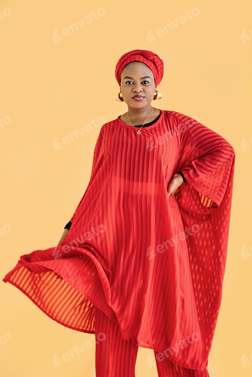 Preview: Portrait of charming pleasant African woman wearing red traditional red suit and turban, looking at