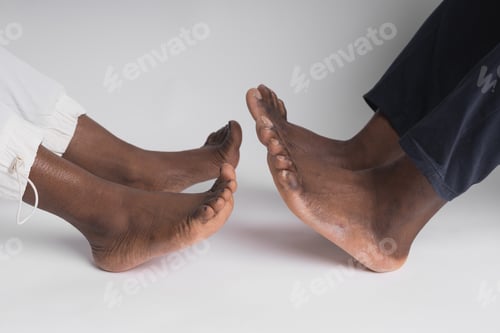 Preview: Close up African American man and woman legs touching holding together isolated on white background
