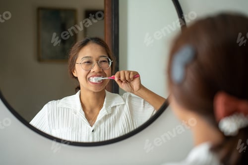 Preview: morning brushing teeth. Young woman brushing teeth with toothbrush and looking