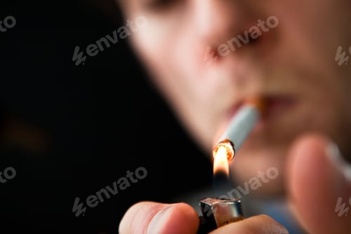 Preview: Man Lighting A Cigarette Against A Black Background