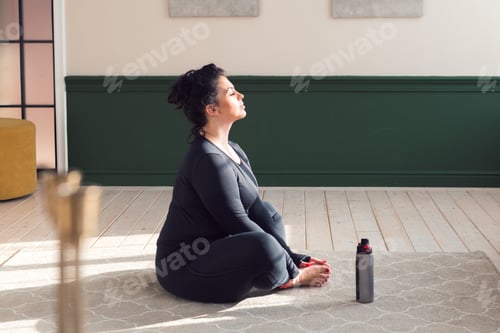 Preview: pluse size woman doing exercise, meditation or fitness, stretching at home
