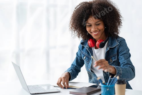 Preview: Attractive smiling African American businesswoman using laptop at office