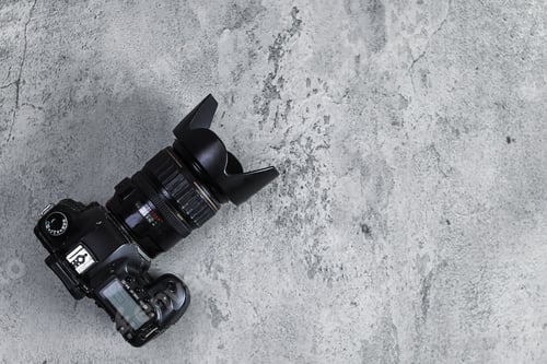 Preview: Flat Lay Of Professional DSLR Camera With Lens Rests On Textured Concrete Surface