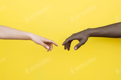 Aperçu: Main blanche et main noire sur le point de toucher sur fond jaune