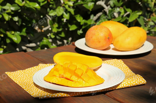 Preview: Plates with tasty mango on wooden table outdoors