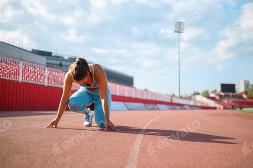 Preview: A female runner in start position on running track at stadium.