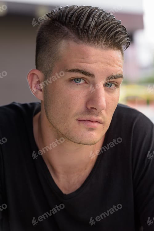 Preview: Face of young handsome man sitting outdoors