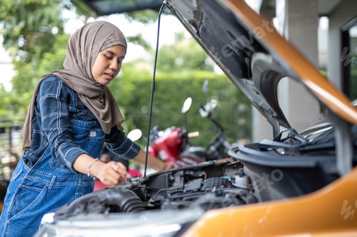 Preview: Asian muslim wear hijab woman checking up automobile engine before departure. Female trying