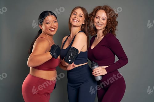 Preview: Three young women in sports clothes and gym accessories in studio shot