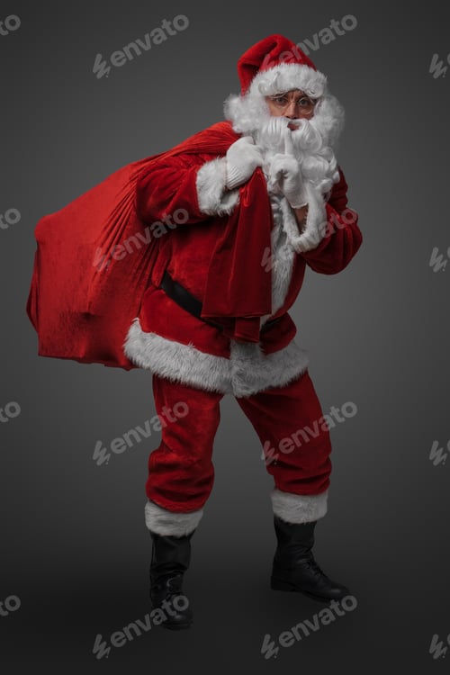 Preview: Santa carrying huge bag with gifts looking at camera