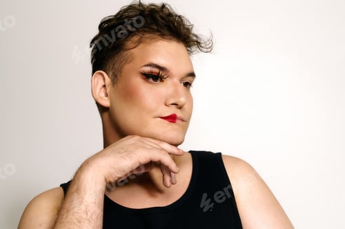 Preview: Unique and appealing queer individual showcasing vibrant makeup artistry in a studio setting