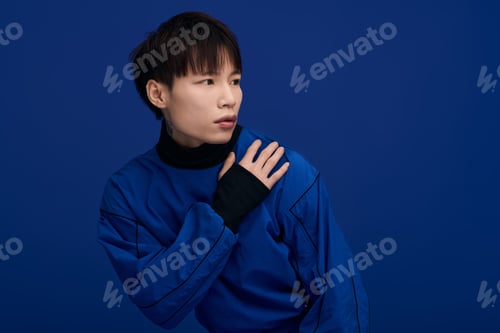 Preview: Captivating young man in vibrant blue attire poses against a bold navy background