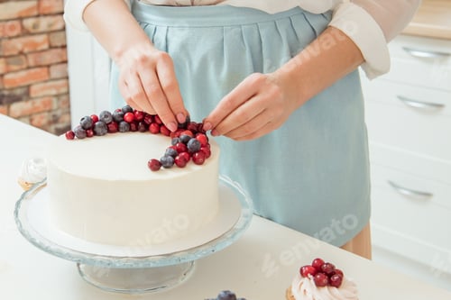 Preview: Women's hands decorated with red and blue berries white birthday cake