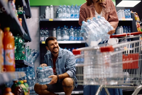 Preview: Happy man and his wife buying drinking water plastic bottles in supermarket.
