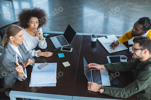 Preview: high angle view of multicultural businesspeople at meeting in office