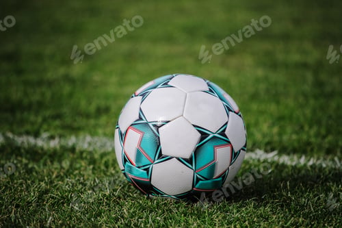 Preview: Shallow focus of a football ball on empty field with fresh green grass