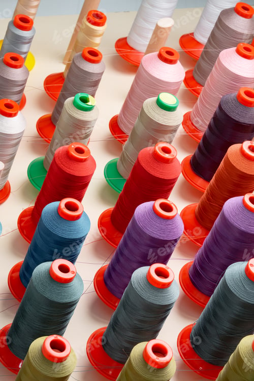 Preview: Row of multicolored thread spools at sewing factory