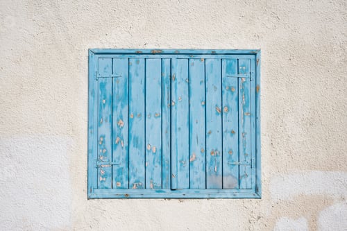 Preview: Cyprus, Larnaca. Blue wooden, peeled window, shutters on pink wall. Facade of building, closeup.