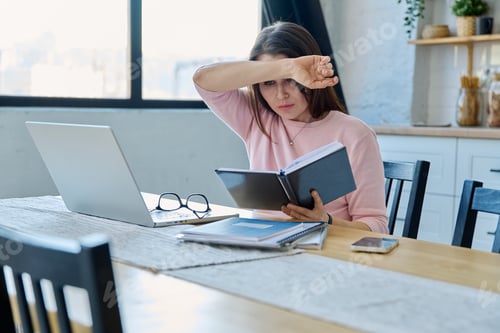 Preview: Middle aged sad stressed woman sitting at home office at table with computer