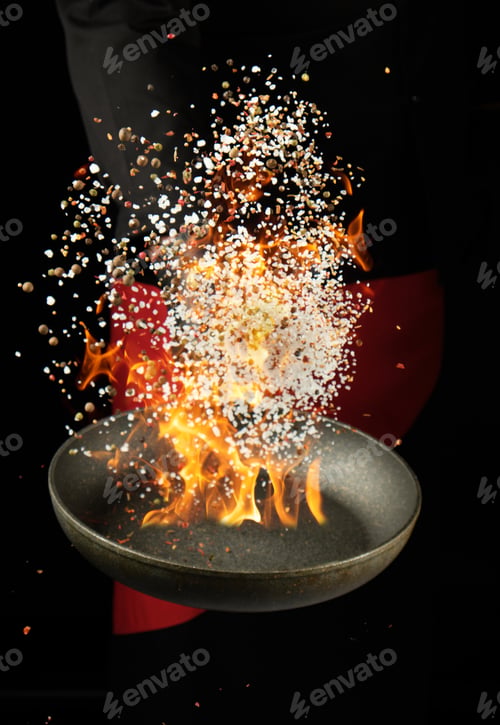 Preview: Chef holds a round pan and throws the mixture of spices and white salt up