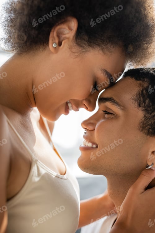 Preview: side view of african american couple smiling face to face at home