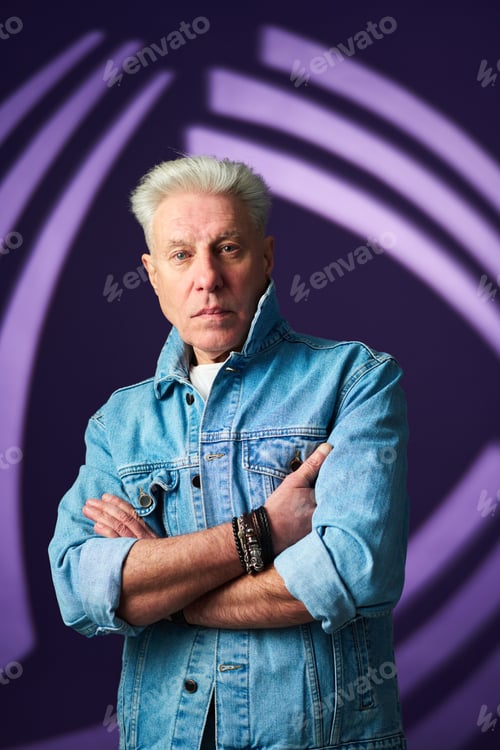 Preview: Serious mature man in blue denim jacket and accessories on wrists