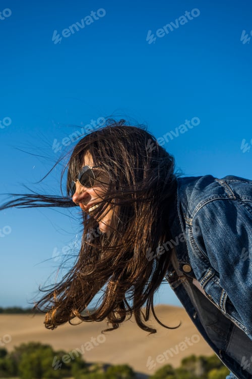 Preview: Side view of a woman laughing out loud outdoors.