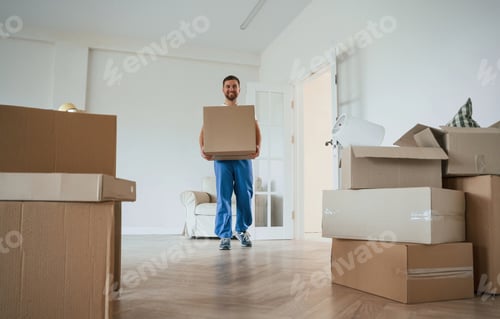 Preview: White shirt and blue uniform. With box in hands. Moving service employee in a room
