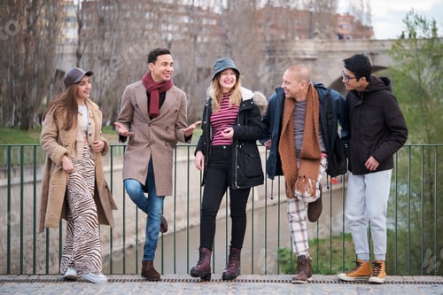 Preview: Group of friends of different ages and ethnicities talk and laugh outdoors.