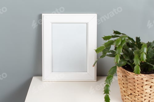 Preview: Front view of white poster frame mockup with plant in a pot