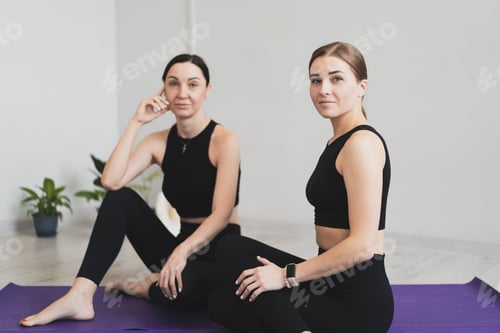 Preview: Young women sit on yoga mats to start practicing meditation and yoga at home