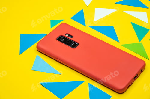 Preview: Closeup shot of a red smartphone on a yellow paper surface