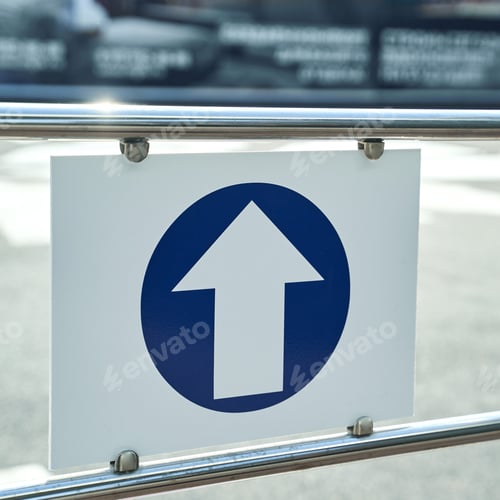 Preview: Directional sign with arrow on metal rail at urban crosswalk in daylight