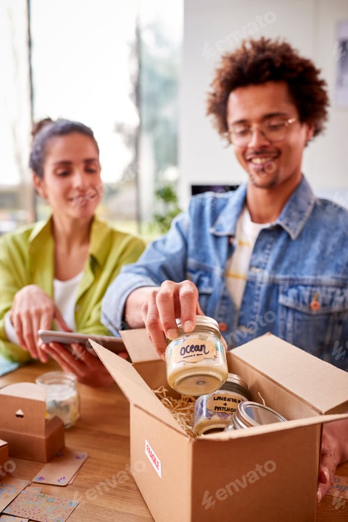 Preview: Young Couple Running Online Business From Home Packing Boutique Candles Ready For Shipping