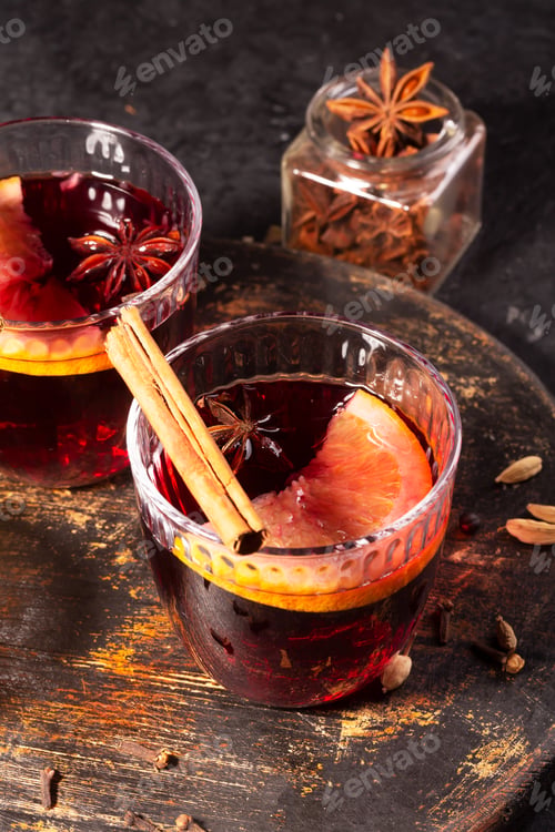 Preview: Mulled wine with slice of orange and spices on a wooden cutting board