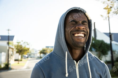 Preview: Portrait of man wearing hooded top eyes closed laughing