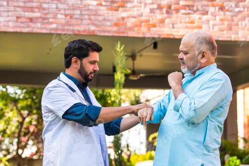 Preview: Elderly Indian man consults with a young doctor outdoors, discussing health in a hospital park