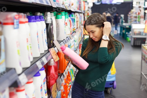 Preview: Woman choosing laundry detergent in grocery store.