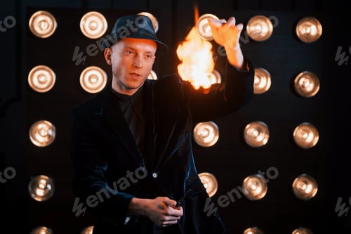 Preview: Controlling the flame. Professional magician showing trick. Light bulbs on background