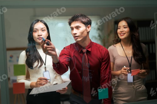 Preview: Business team collaborating on glass board developing strategy