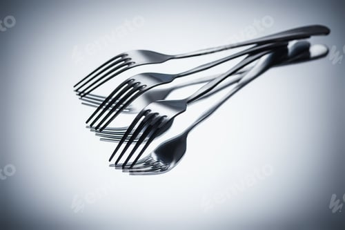 Preview: close-up view of set of shiny metal forks on grey