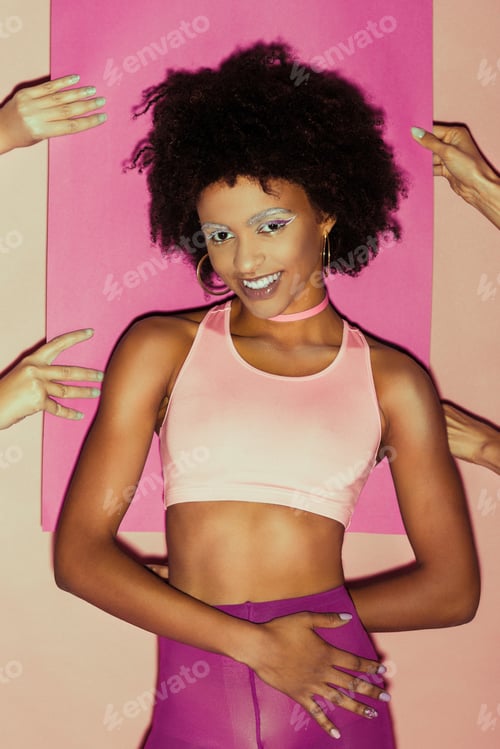 Preview: smiling african american 80s girl in pink clothes posing with pink paper behind