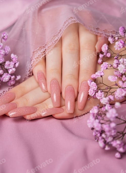 Preview: Female hands with pink nail design hold gypsophila flowers.