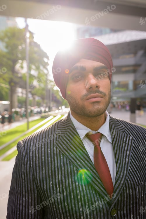 Preview: Portrait of Indian businessman outdoors in city with lens flare